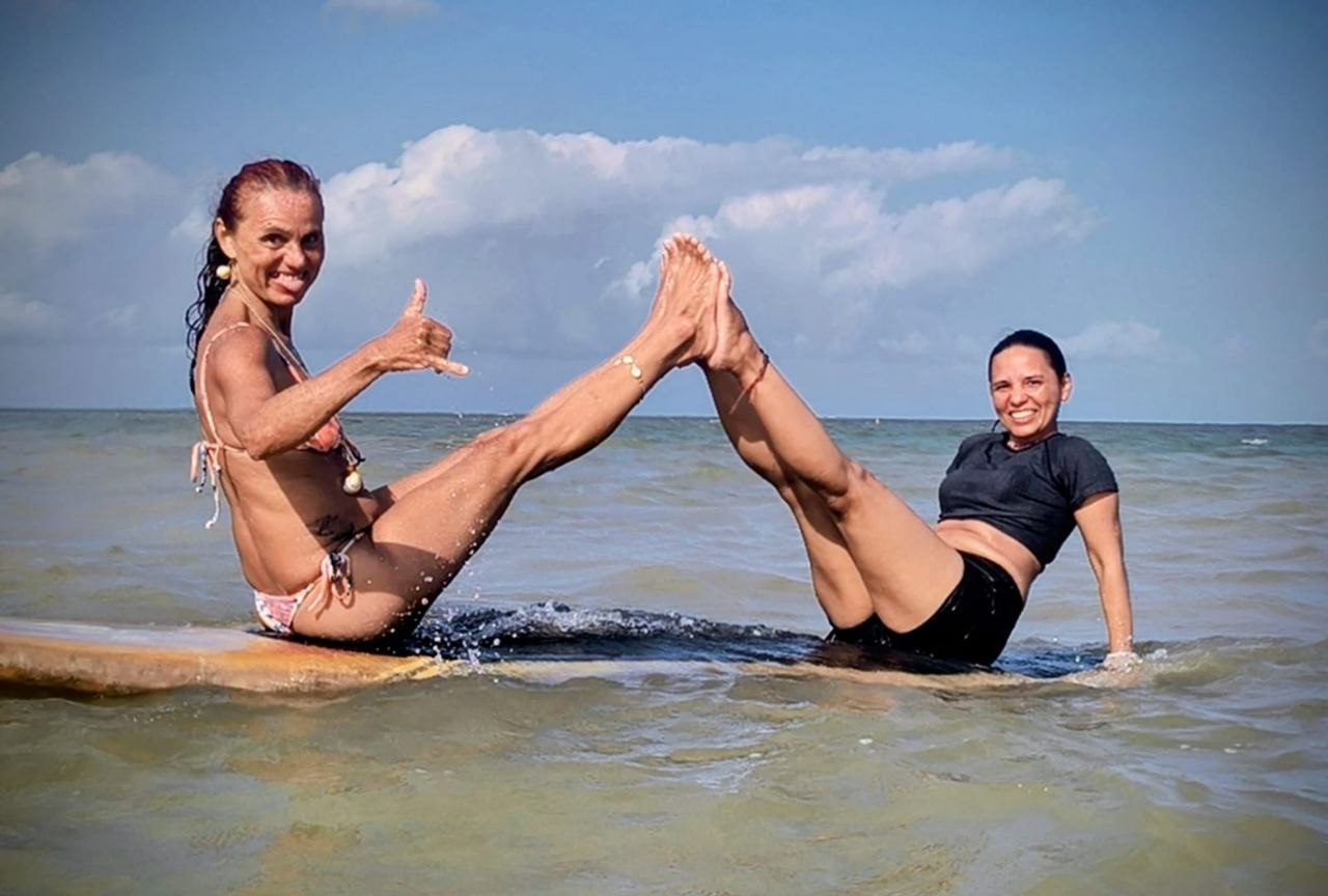 Duas instrutoras praticando SUP Yoga no mar de João Pessoa, em postura de equilíbrio sobre pranchas de stand up paddle
